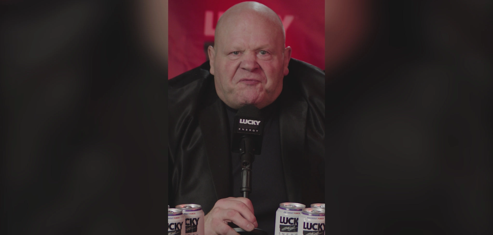Video still from the Lucky Energy site: a man speaking at a microphone
